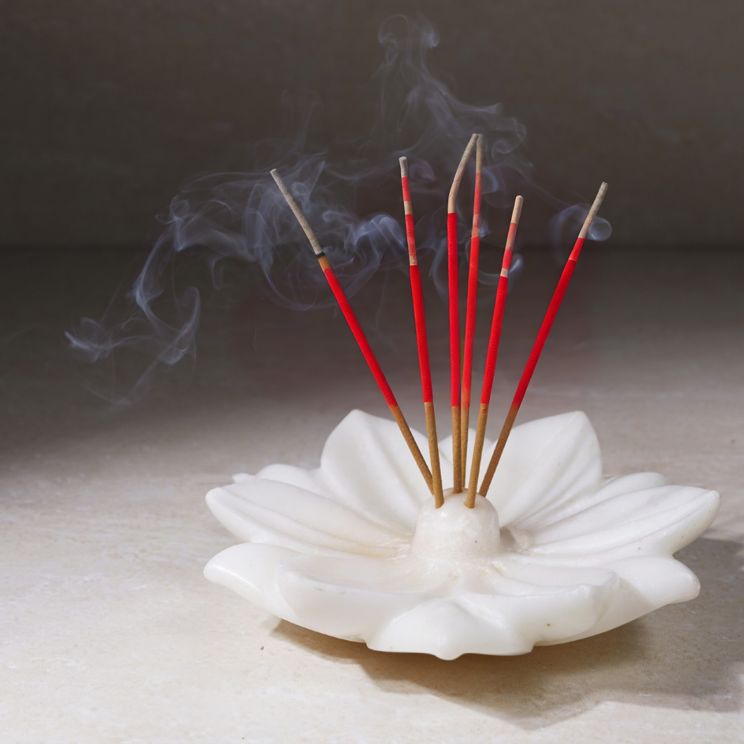 Incense burner with red incense sticks and smoke on a dark background